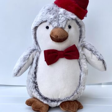 a stuffed penguin wearing a red hat and bow tie